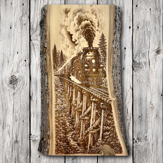 Union Pacific Big Boy 4014 steam locomotive crossing a wooden railroad trestle through a mountain forest, laser engraved on natural live edge hardwood with bark edges.