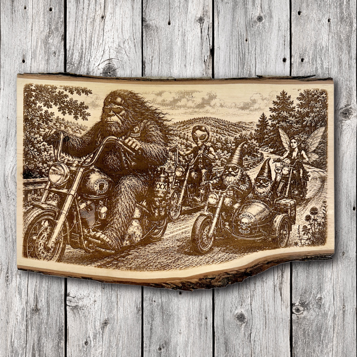 Handcrafted live edge engraved wood wall art depicting Bigfoot riding a motorcycle alongside an alien biker, woodland gnomes in a motorcycle sidecar, and a fairy riding through a scenic mountain forest.
