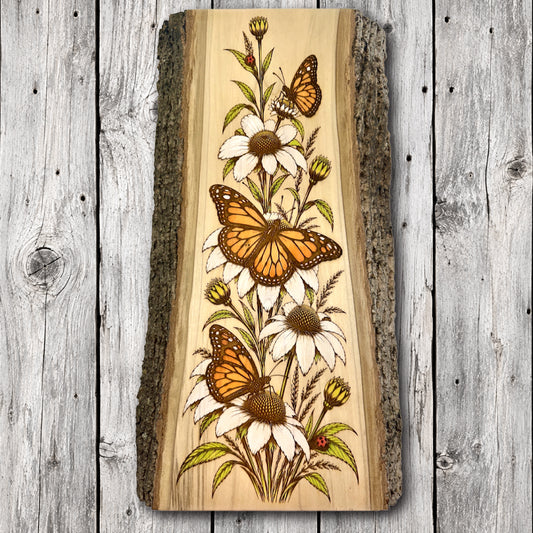 Hand-painted monarch butterflies surrounded by white wildflowers on laser engraved live edge hardwood wall art with natural bark edges.
