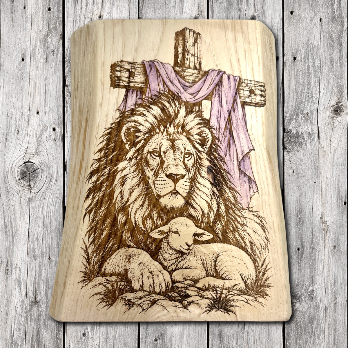 Christian live edge wood wall art featuring a majestic lion resting beside a peaceful lamb beneath a rustic wooden cross draped with hand-painted purple cloth.