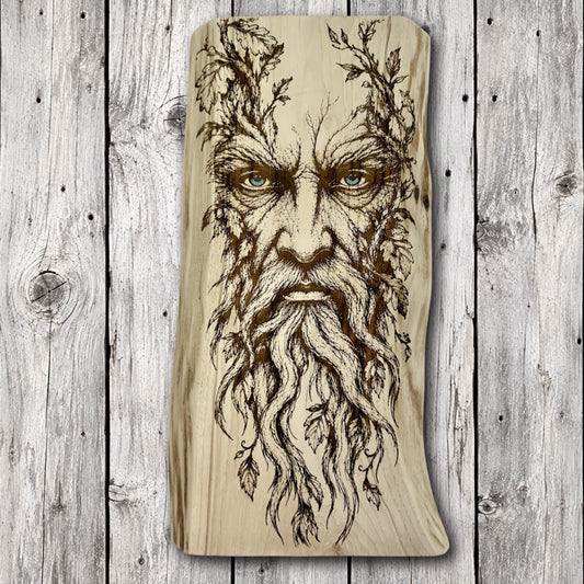 Handcrafted live edge wood wall art featuring a detailed laser engraving of a mystical Green Man forest guardian with a flowing beard of twisted roots, leafy branches, and striking blue eyes.