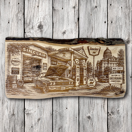 Handcrafted live edge engraved wood wall art depicting a vintage Sinclair gas station in Greensburg, Pennsylvania, featuring a classic Chevrolet Chevelle SS, antique gas pumps, retro automotive signs, and a historic downtown streetscape.