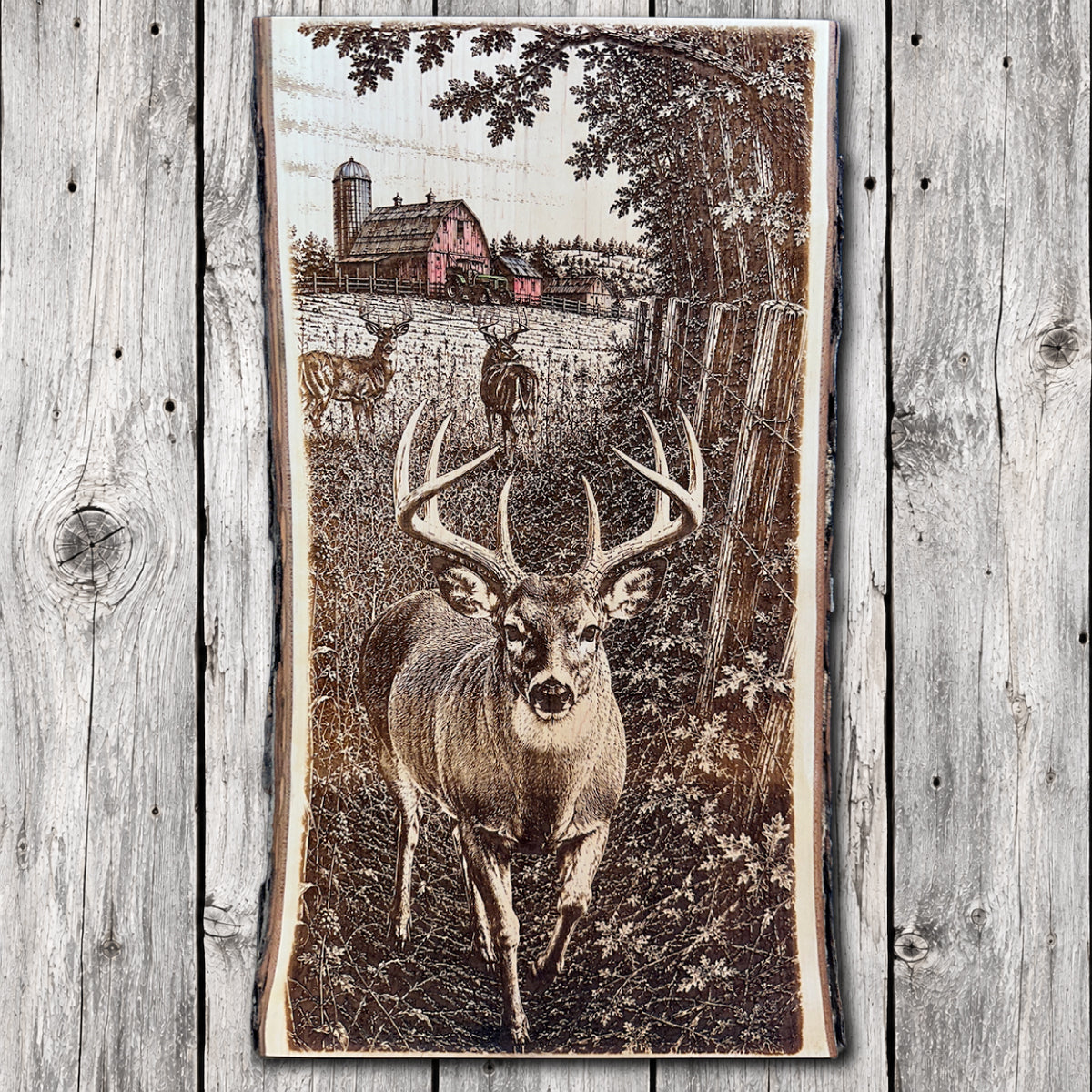Live edge hardwood wall art featuring a large whitetail buck, two distant deer, rustic wooden fence, and red barn with hand-painted accents.